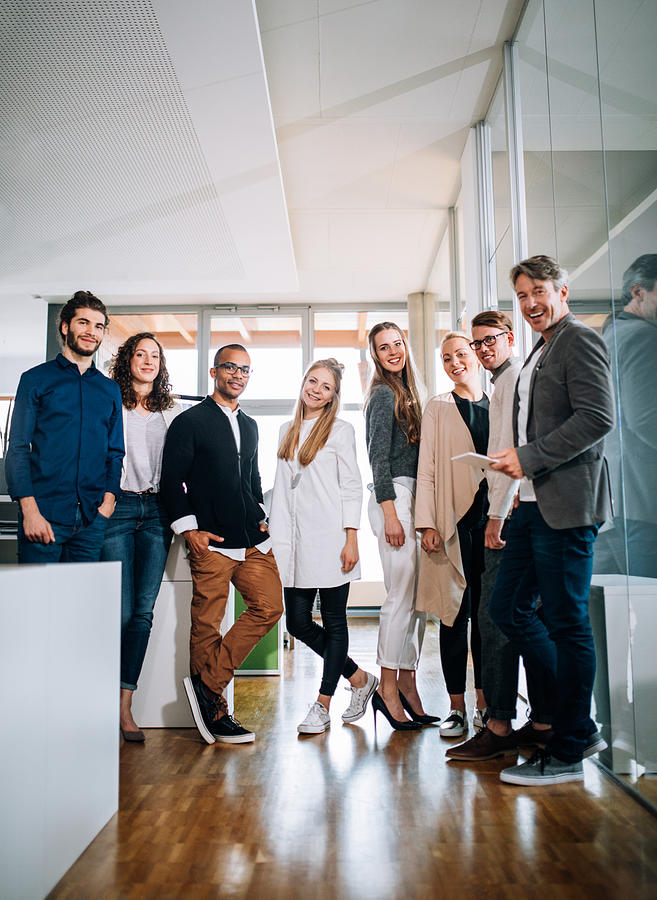 Multi-cultural group employees standing together during a office studio meeting. Photograph by Wundervisuals
