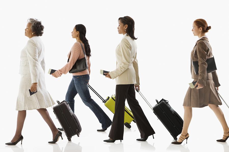 Multi-ethnic businesswomen pulling suitcases Photograph by Jose Luis Pelaez Inc