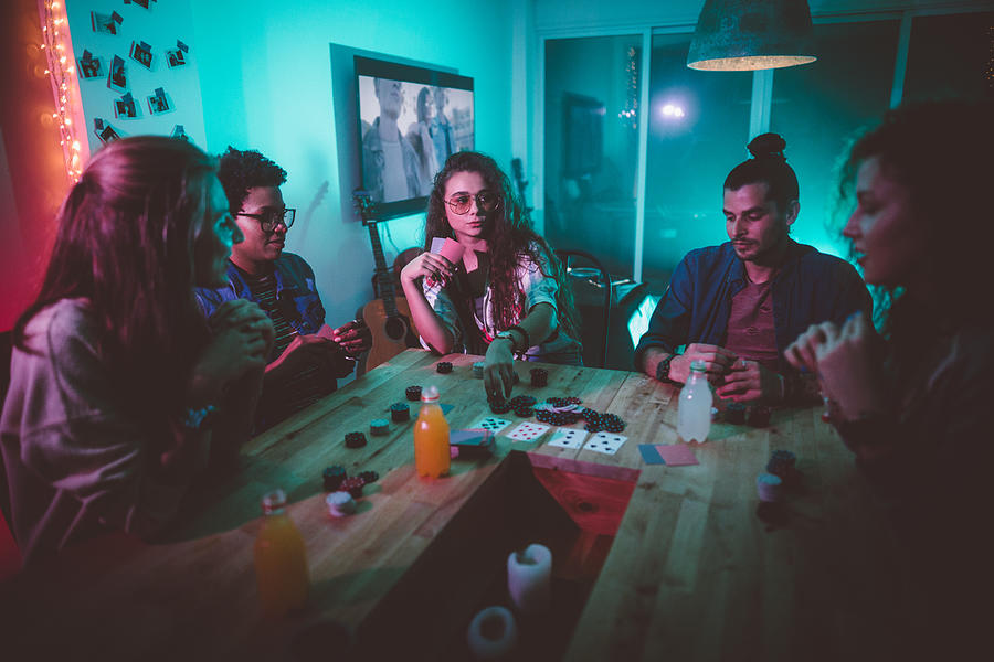 Multi-ethnic hipster friends playing poker at home Photograph by Wundervisuals