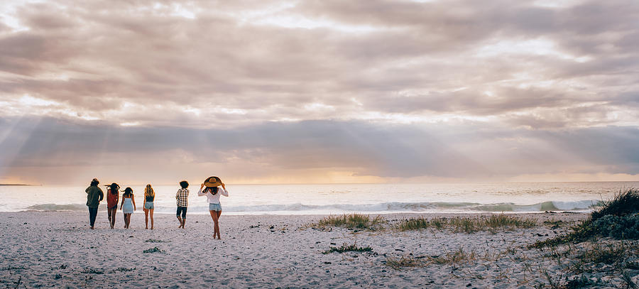 Multi-Ethnic Hipster Friends Walking on Sandy Beach Photograph by Wundervisuals