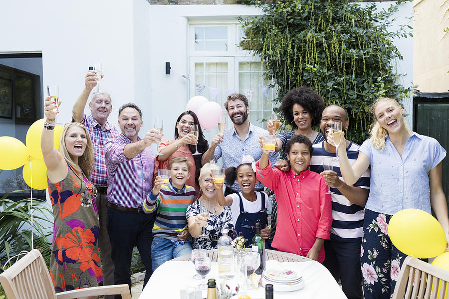 Multi generation family toasting with champagne glasses at party on garden patio Photograph by Compassionate Eye Foundation/Robert Daly