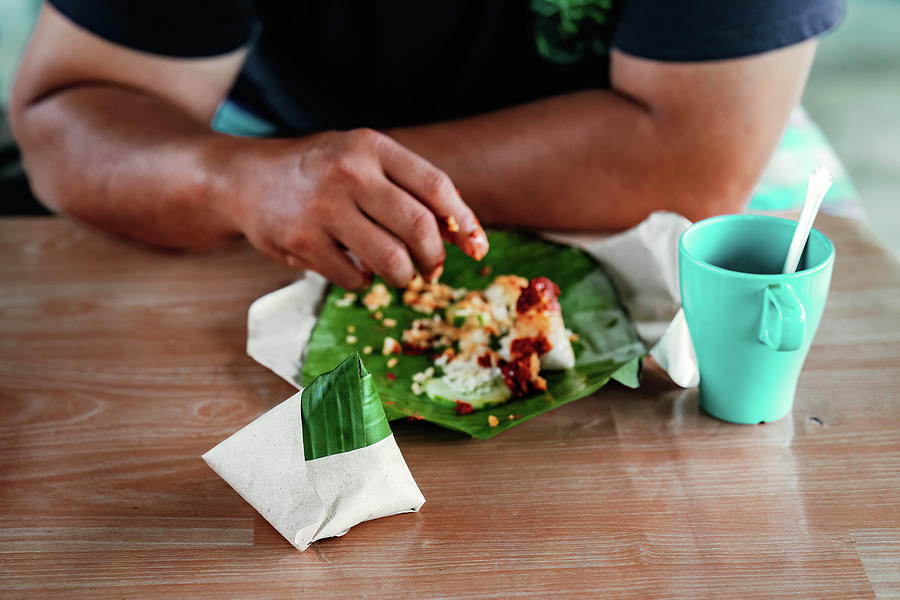 Nasi Lemak Wrapped In Banana Leaf With Brown Paper With People Eating