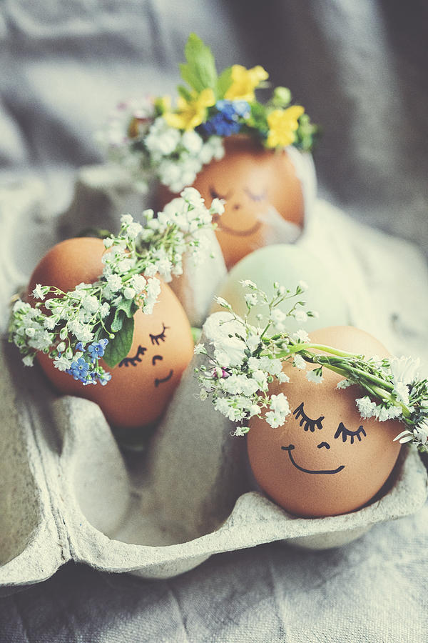 Natural easter eggs with funny painted face and sweet flower wreath Photograph by Rike_