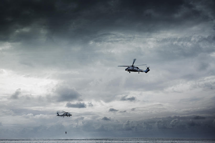 Navy helicopters pulling man out of water. Photograph by Dana Neibert