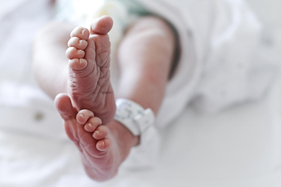 Newborn baby boy at hospital with identity tag on feet, close up Photograph by Isabel Pavia