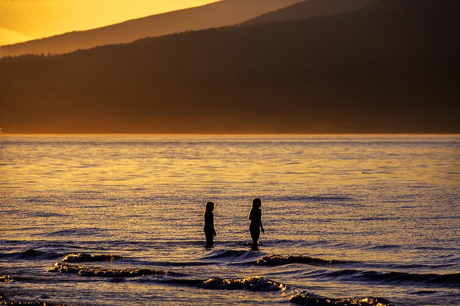 nonrecognizable young girls playing in the sea at sunset, Kitsina Beach, Vancouver, British Columbia, Canada Photograph by Pierre Longnus