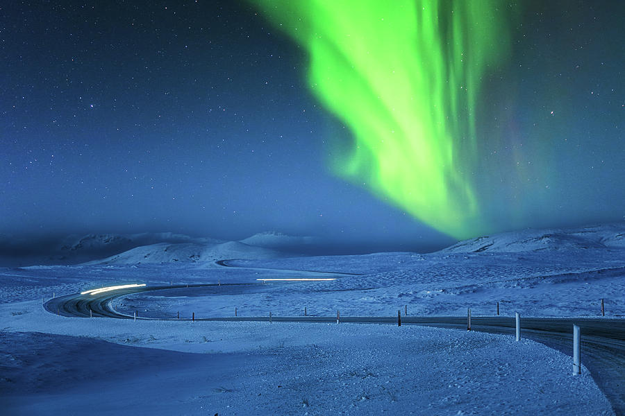 Northern Lights above snow covered icelandic winding road Photograph by Mihai Andritoiu