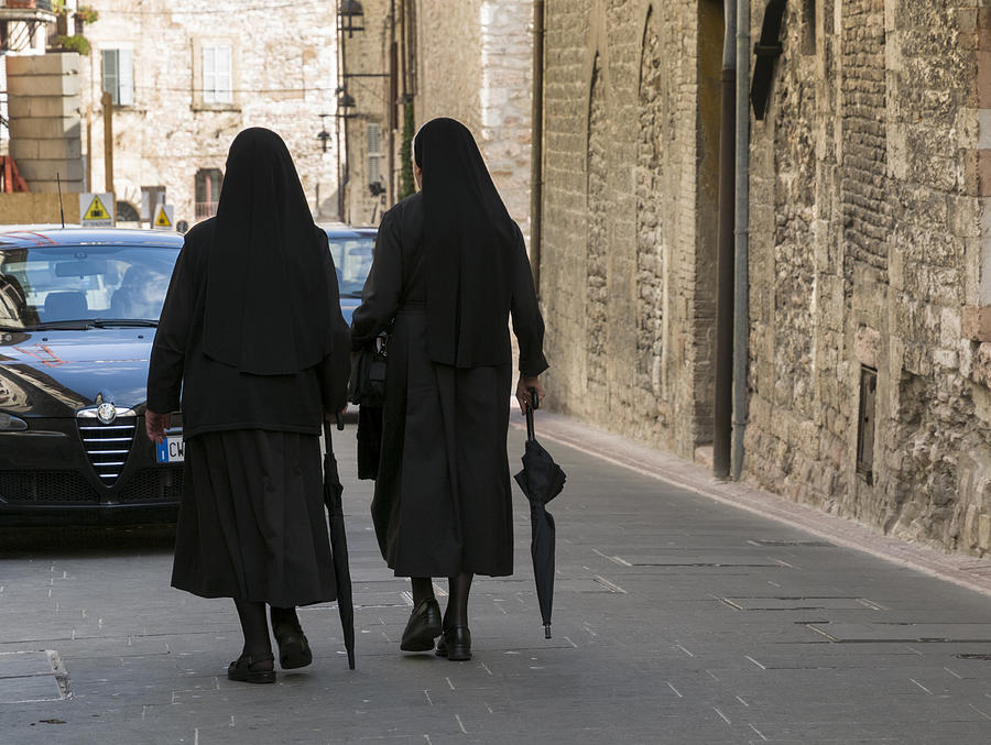 Nuns with umbrellas walking against traffic. Photograph by Stuart McCall