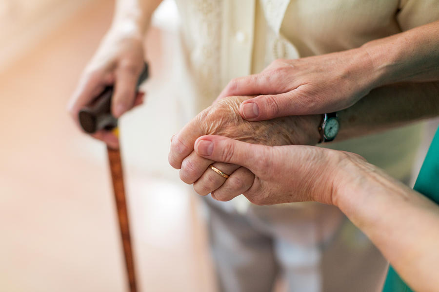 Nurse consoling her elderly patient by holding her hands Photograph by Piksel