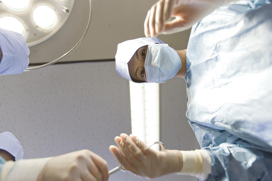 Nurse handing surgeon instrument in operating room, low angle view Photograph by Michael H