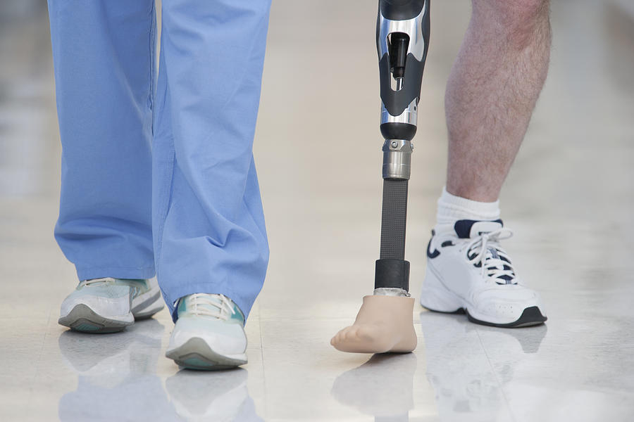 Nurse helping man walk with prosthetic leg Photograph by ER Productions Limited