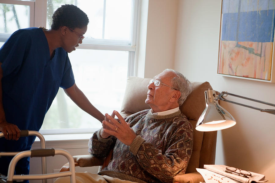 Nurse looking after senior man at home Photograph by Image Source