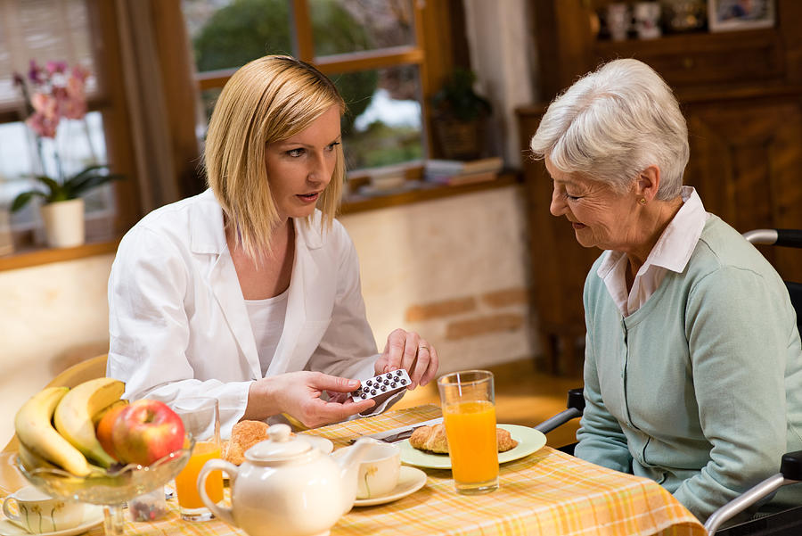 Nurse showing medicines to senior woman Photograph by Simonkr