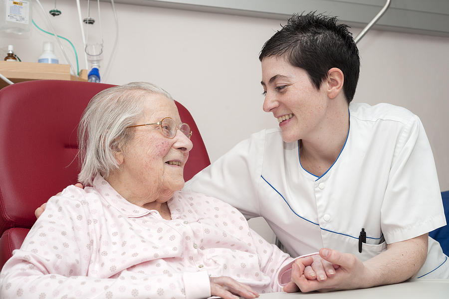 Nurse smiling with senior patient Photograph by Thierry Dosogne