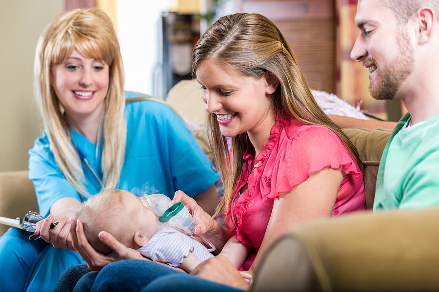 Nurse teaching parents how to give newborn baby breathing treatment Photograph by SDI Productions