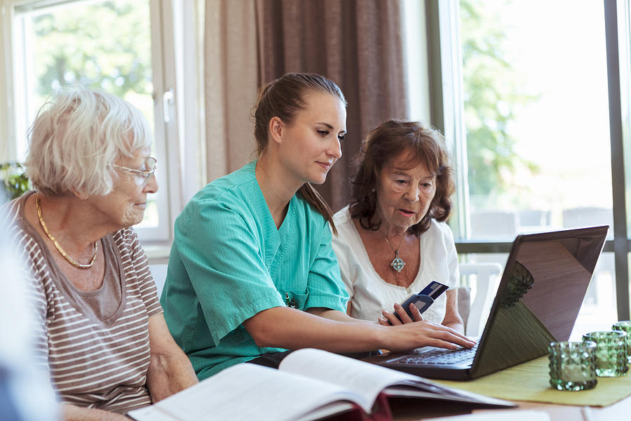 Nurse with senior women buying medicine online using laptop and credit card at nursing home Photograph by Kentaroo Tryman