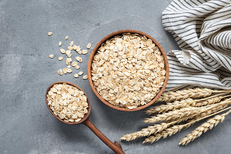 Oats, rolled oats or oat flakes in wooden bowl Photograph by Arx0nt