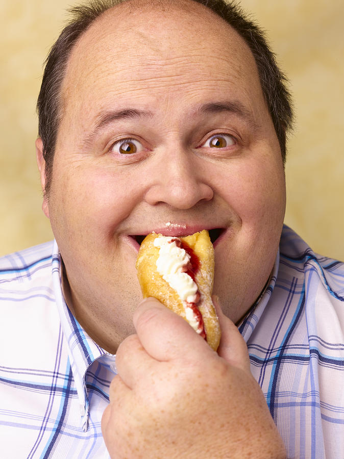 Obese man eating cream cake. Photograph by Peter Dazeley
