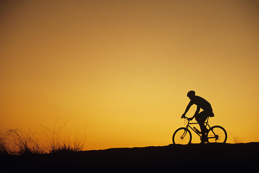 Off-road biker at sunset, Discovery Park, Seattle, Washington, USA Photograph by Karl Weatherly
