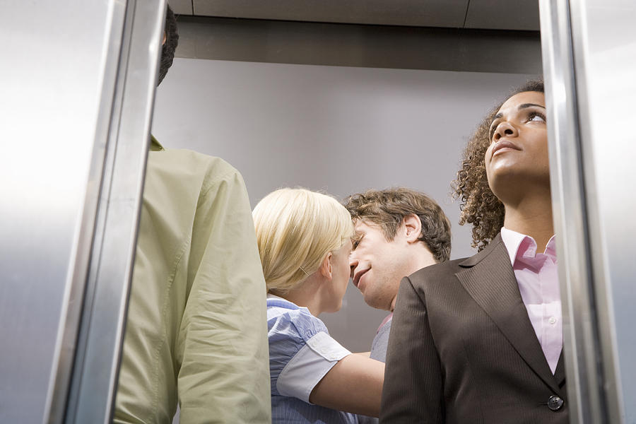 Office couples kissing in elevator Photograph by Paul Burns