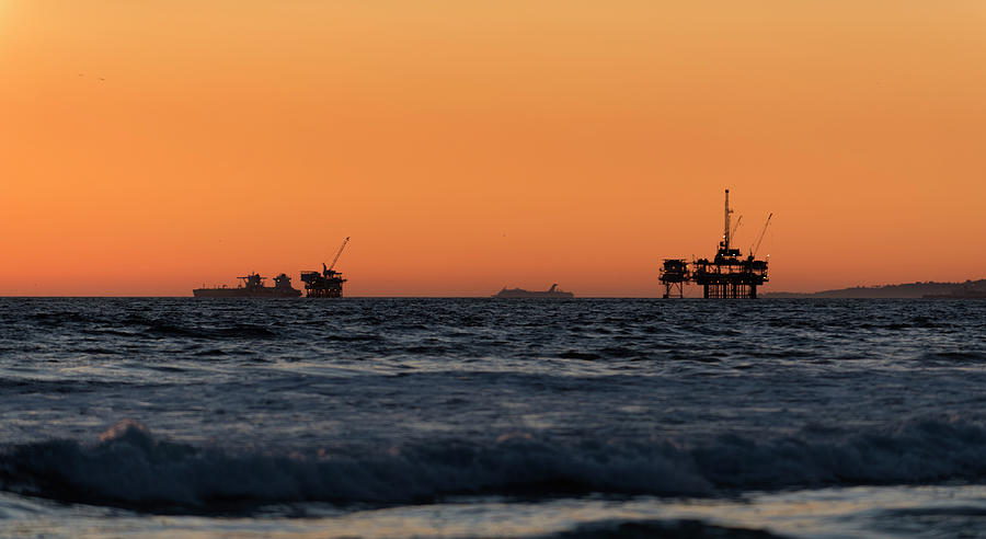 Offshore oil drilling rigs at sunset Photograph by Mark Stout