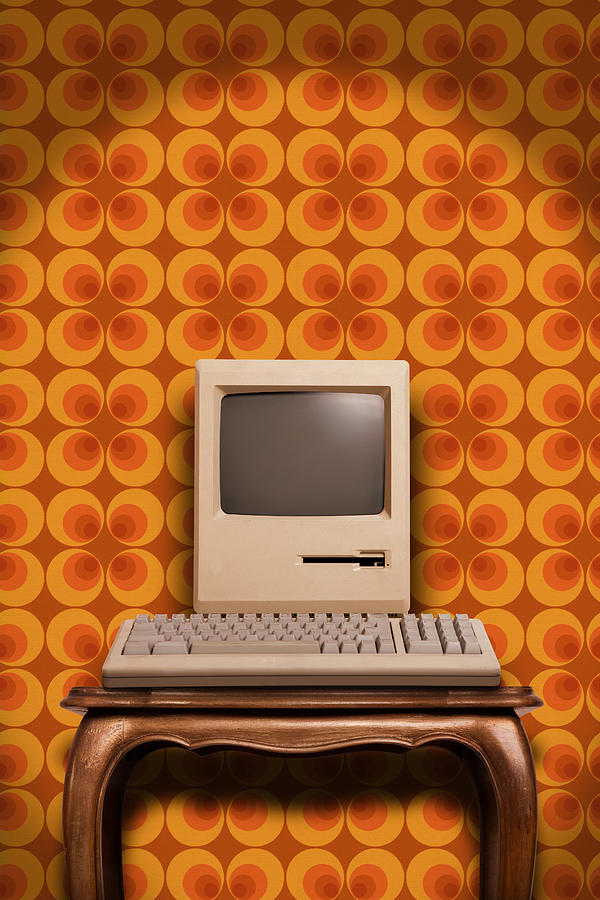 Old desktop computer on wooden table and seventies wallpaper Photograph by Maxiphoto