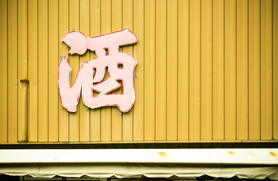 Old liquor sign on weathered wall above awning in Yokohama Photograph by DigiPub