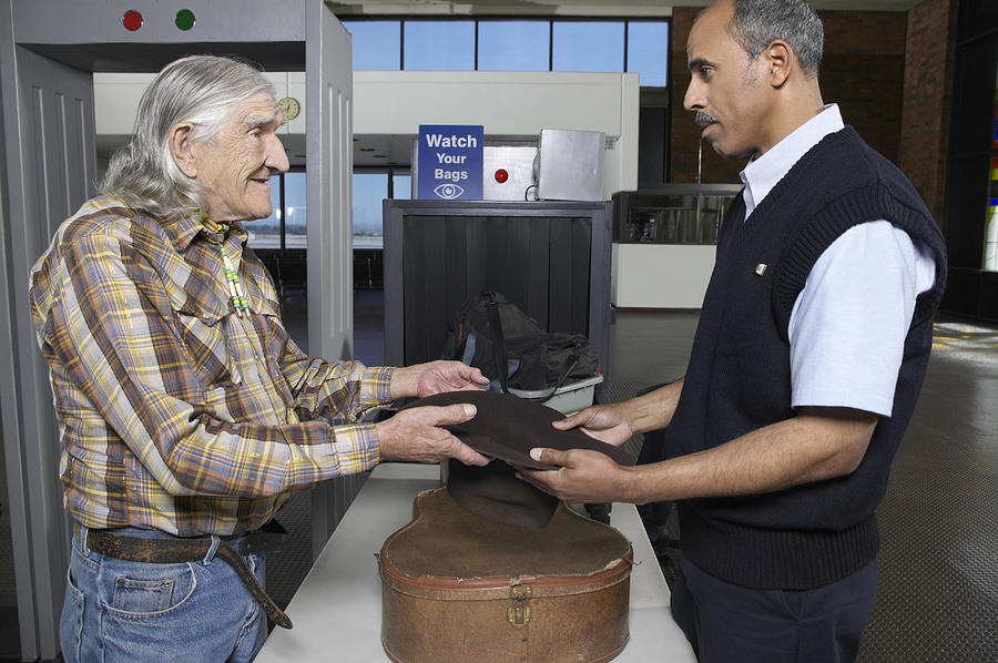 Old Male Cowboy at an Airport Security Check Showing a Customs Official His Empty Hat Photograph by Digital Vision.