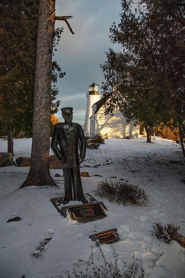 Old Presque Isle Lighthouse in Michigan along Lake Huron in the winter light keeper statue Photograph by Eldon McGraw