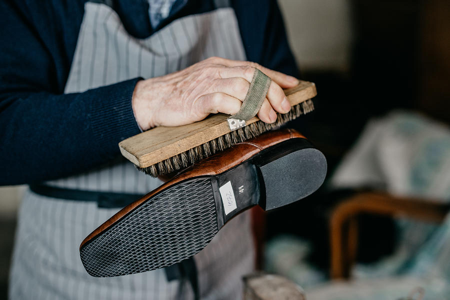 Old shoemaker is polishing a shoe Photograph by Anchiy