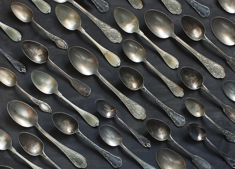 Old vintage metal spoons on black background. Photograph by Twomeows