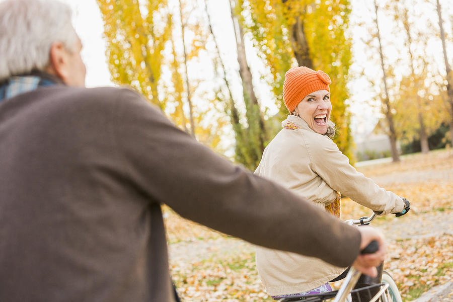 Older Caucasian couple riding bicycles on autumn leaves Photograph by Mike Kemp
