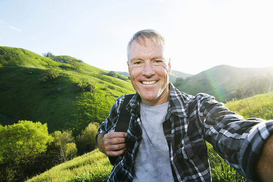 Older Caucasian man taking selfie on rural hilltop Photograph by Peathegee Inc