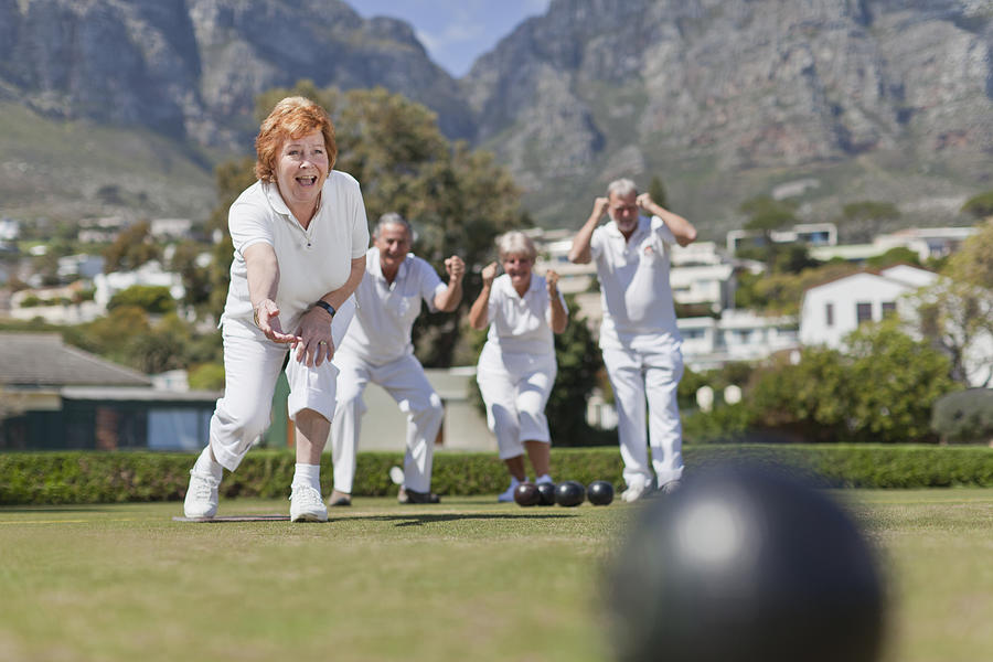 Older couples playing lawn bowling Photograph by Hybrid Images