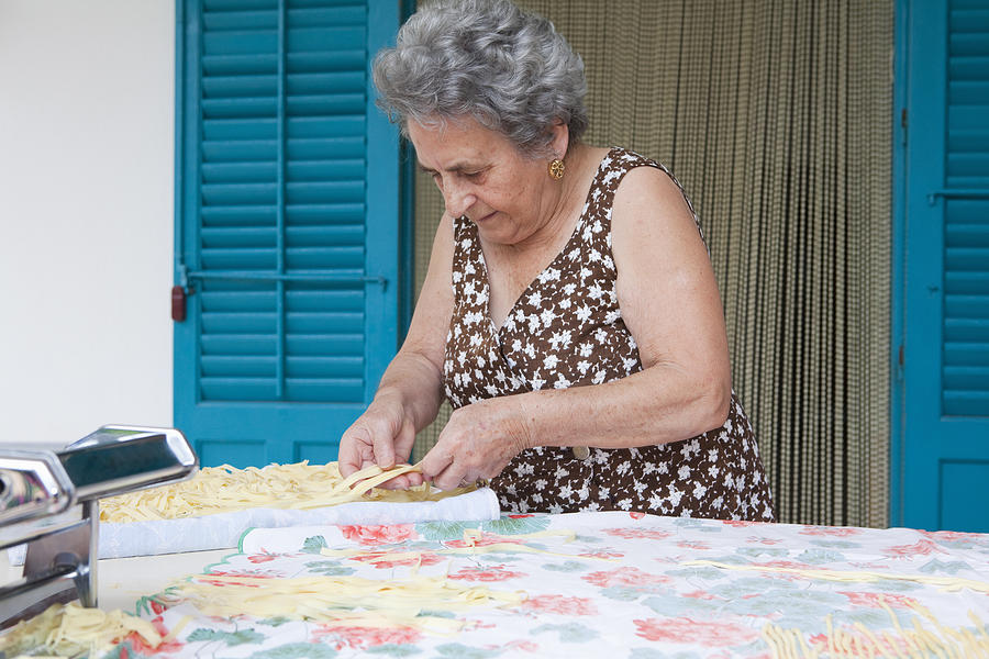 Older woman making pasta with roller Photograph by Judith Haeusler
