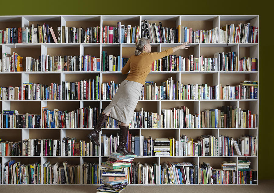 Older woman standing on stack of books Photograph by Tim Macpherson