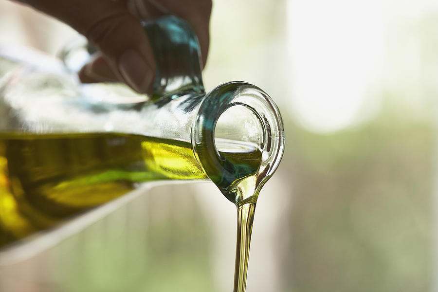Olive oil pouring from bottle Photograph by Fancy/Veer/Corbis