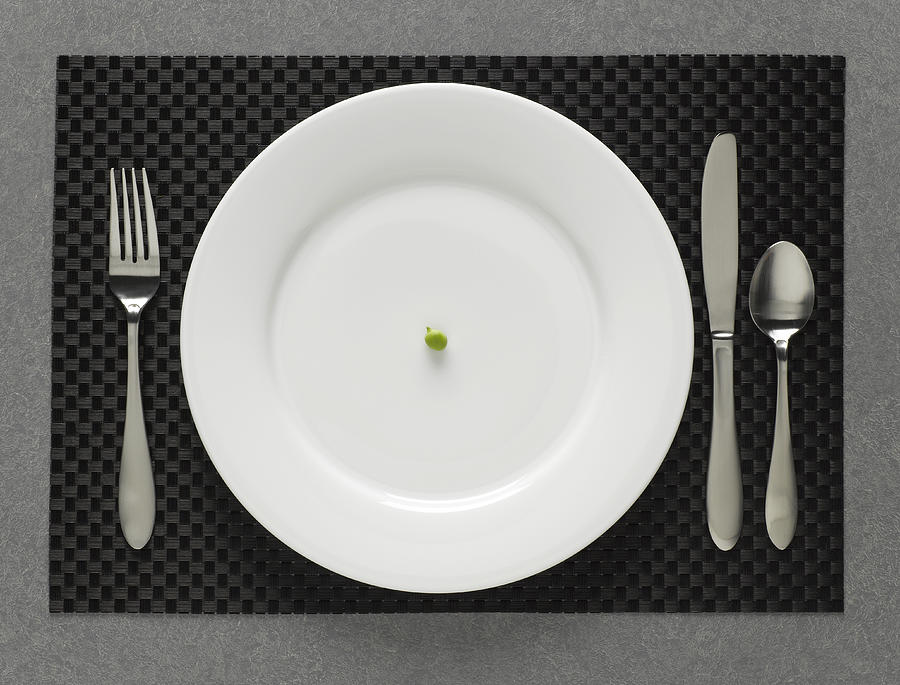 One green pea on white plate with table setting, elevated view Photograph by Jeffrey Coolidge