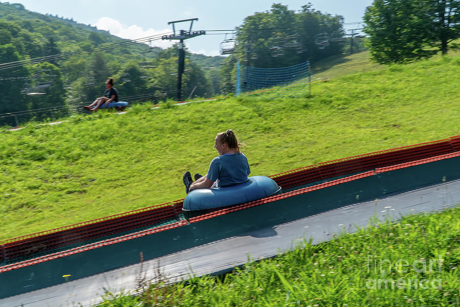 One vacationer slides down a tube ride while another is towed ba