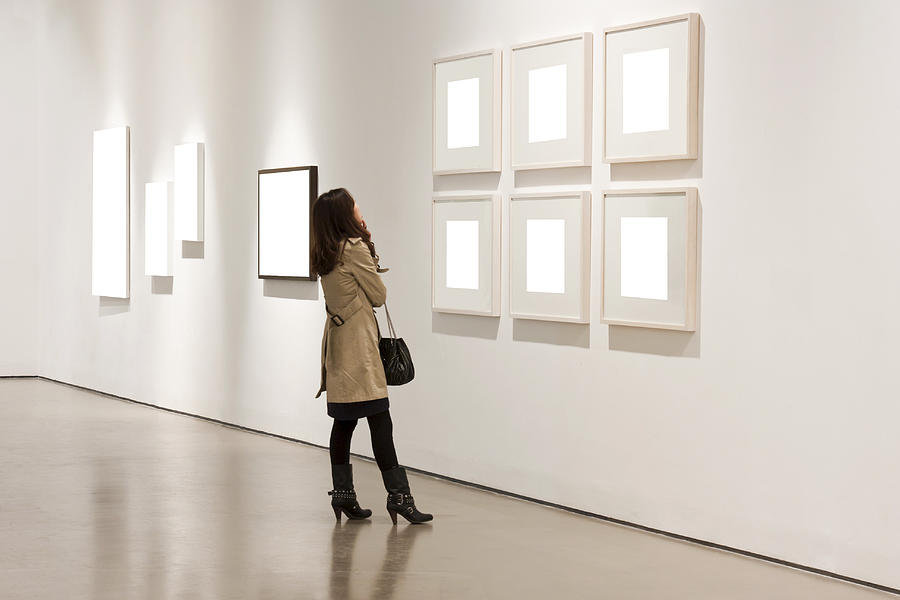 One woman looking at white frames in an art gallery Photograph by Loonger