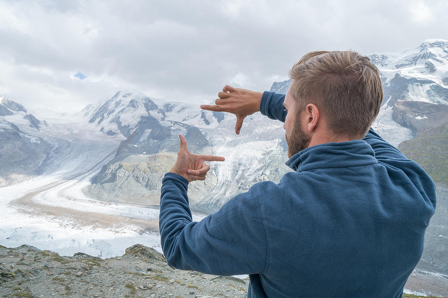 One young man framing glacier with hands, Switzerland Photograph by Swissmediavision