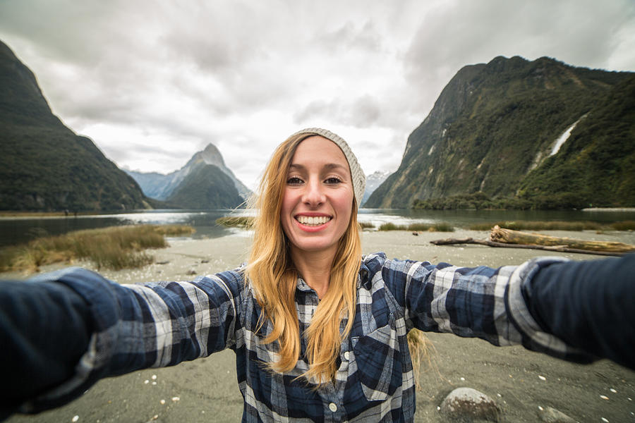 One young woman traveling takes selfie portrait with mountain landscape Photograph by Swissmediavision