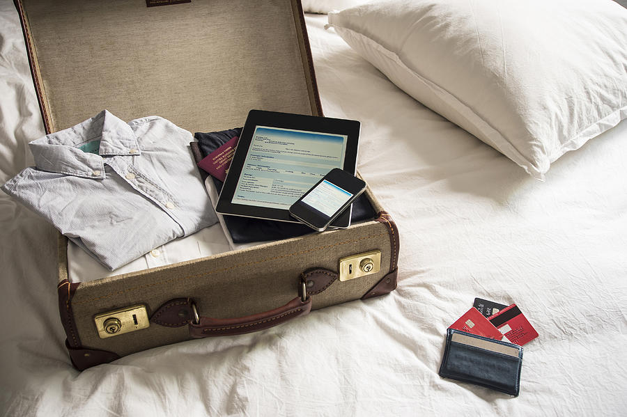 Open suitcase on bed with digital tablet and mobile phone Photograph by David Cleveland