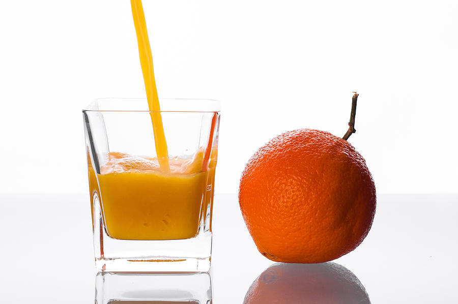 Orange juice pouring into glass Photograph by MichalDziedziak