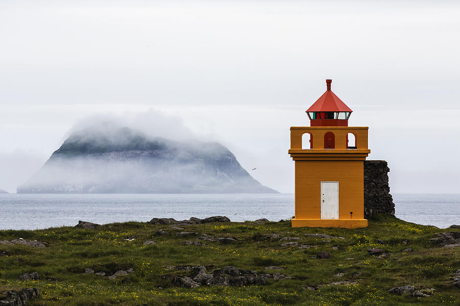Orange lighthouse on rocky remote cliff Photograph by Jeremy Woodhouse