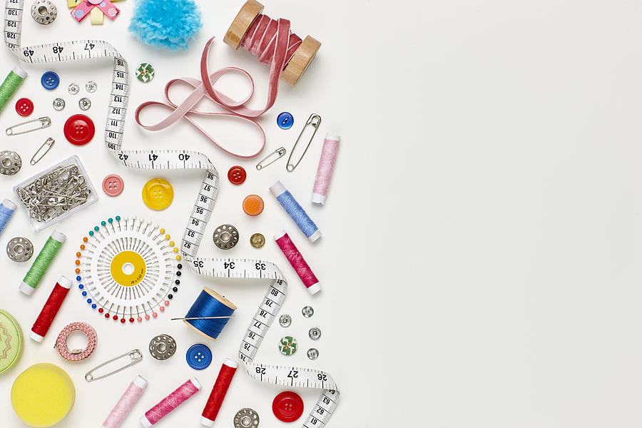 Overhead flat lay of colorful sewing items on white background Photograph by Neustockimages