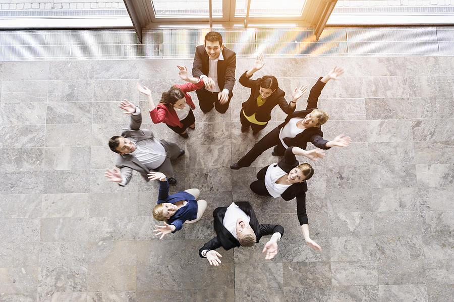 Overhead view of business team in circle jumping for joy Photograph by Suedhang