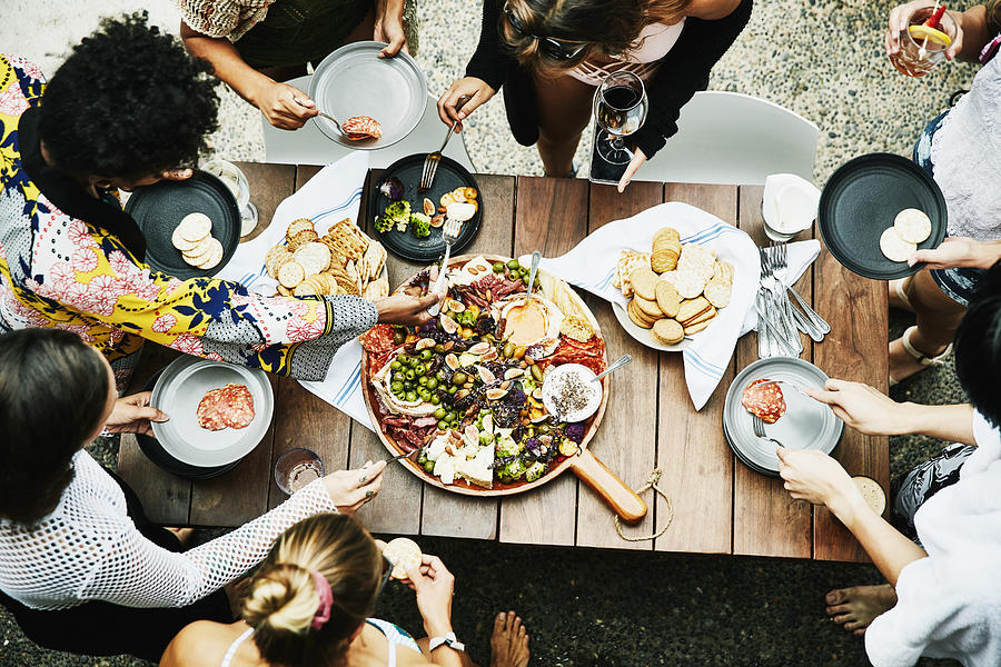 Overhead view of group of friends enjoying buffet of food during party Photograph by Thomas Barwick