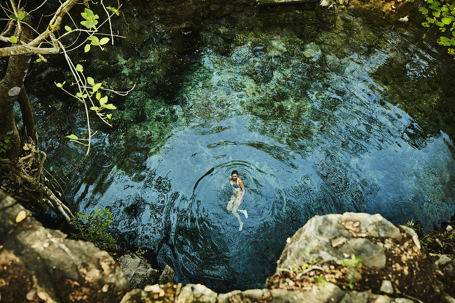 Overhead view of woman swimming in cenote while on vacation Photograph by Thomas Barwick