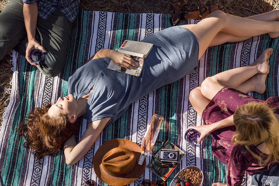 Overhead view young woman with book relaxing on picnic blanket Photograph by Caia Image